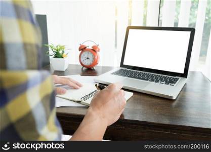 young caucasian man working at home planning work writing note on some project with his laptop on a desk, strartup business, e learning concept.