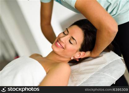 Young caucasian smiling woman receiving a head massage in a spa center with eyes closed. Female patient is receiving treatment by professional therapist.