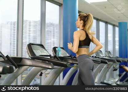 Young caucasian sporty Woman On Running Machine In Gym. Young sporty Woman On Running Machine In Gym