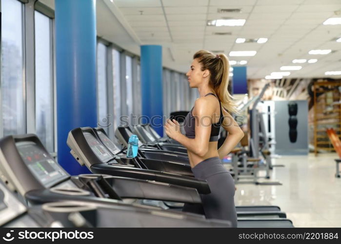 Young caucasian sporty Woman On Running Machine In Gym. Young sporty Woman On Running Machine In Gym