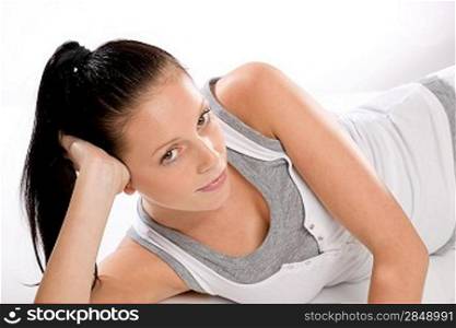 Young Caucasian tired woman lying in sportswear on white background