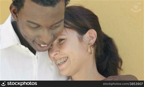 Young caucasian woman and black man hugging and smiling