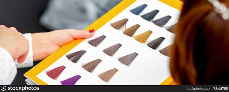 Young caucasian woman choosing a color from the hair color chart in a beauty salon. Young caucasian woman choosing a color from the hair color chart in a beauty salon.
