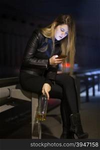 Young caucasian woman drinking alcohol and typing message on street at night