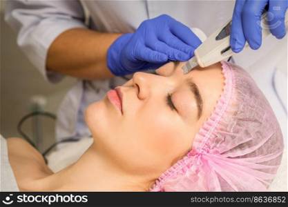 Young caucasian woman having ultrasonic peeling with ultrasound device in a cosmetic beauty salon. Young caucasian woman having ultrasonic peeling with ultrasound device in a cosmetic beauty salon.