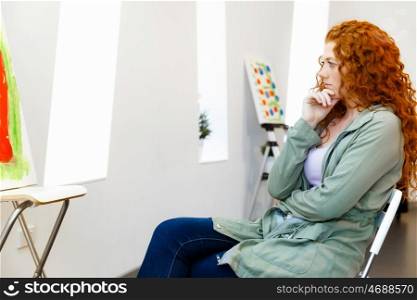 Young caucasian woman in art gallery front of paintings. Young caucasian woman in an art gallery in front of painting displayed on white wall