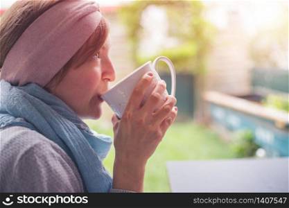 Young Caucasian woman is enjoying a cup of tea on the veranda