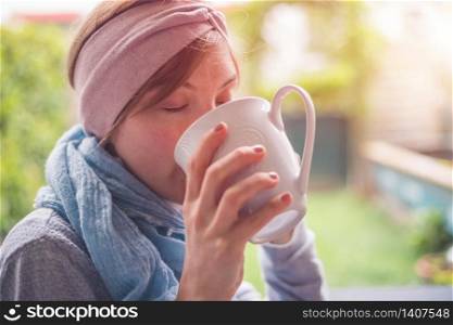 Young Caucasian woman is enjoying a cup of tea on the veranda