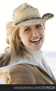 Young Caucasian woman looking at viewer wearing cowboy hat.
