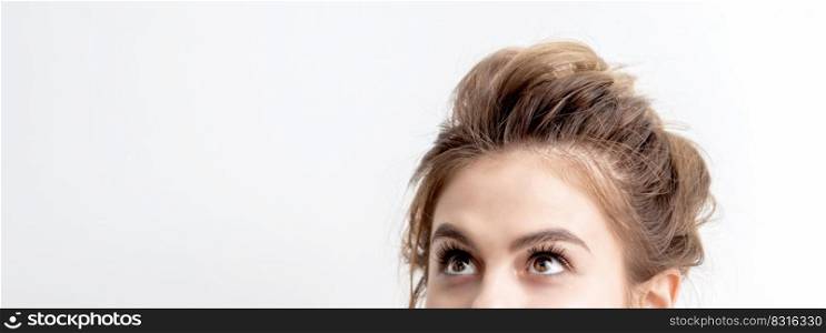 Young caucasian woman looking up on white background. Half face of woman looking upwards, copy space. Woman looking up on white background