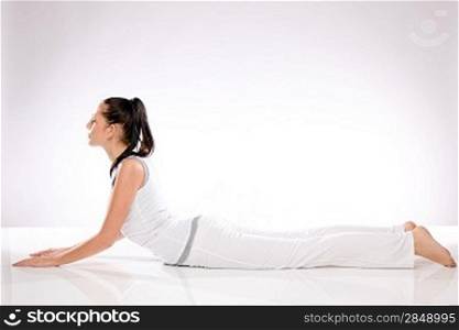 Young Caucasian woman lying in yoga position on white background