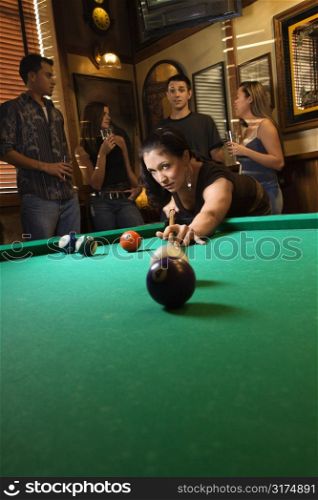 Young caucasian woman preparing to hit pool ball while playing billiards.