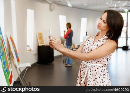 Young caucasian woman standing in art gallery front of paintings. Young caucasian woman standing in an art gallery in front of painting displayed on white wall