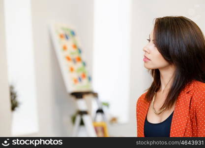 Young caucasian woman standing in art gallery front of paintings. Young caucasian woman standing in an art gallery in front of painting displayed on white wall