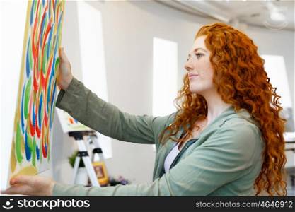 Young caucasian woman standing in art gallery front of paintings. Young caucasian woman standing in an art gallery in front of painting displayed on white wall