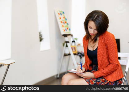 Young caucasian woman standing in art gallery front of paintings. Young caucasian woman standing in an art gallery in front of painting displayed on white wall