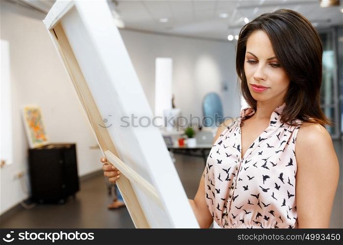 Young caucasian woman standing in art gallery front of paintings. Young caucasian woman standing in an art gallery in front of painting displayed on white wall
