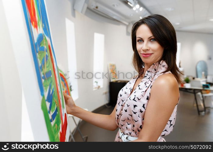 Young caucasian woman standing in art gallery front of paintings. Young caucasian woman standing in an art gallery in front of painting displayed on white wall