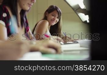 Young caucasian woman studying in high school, portrait of happy female student doing homework in library