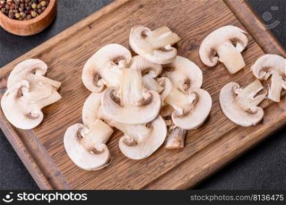 Young ch&ignon mushrooms, sliced into plates, background. Beautiful young white ch&ignons torn to slices on a dark concrete background