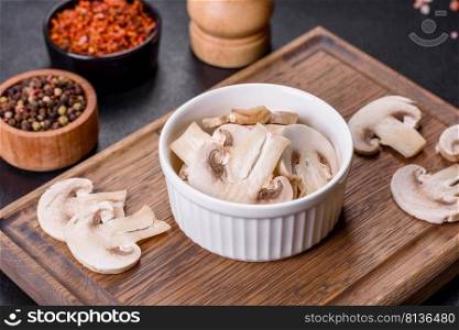 Young ch&ignon mushrooms, sliced into plates, background. Beautiful young white ch&ignons torn to slices on a dark concrete background