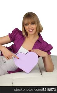 young cheerful blonde on divan with box in shape of heart