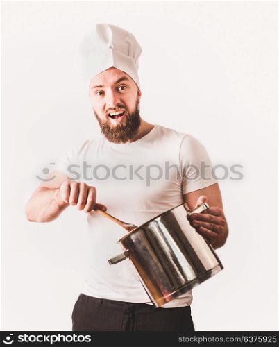 Young cheerful cook man with beard holding pan and spoon on white background. Cooking concept