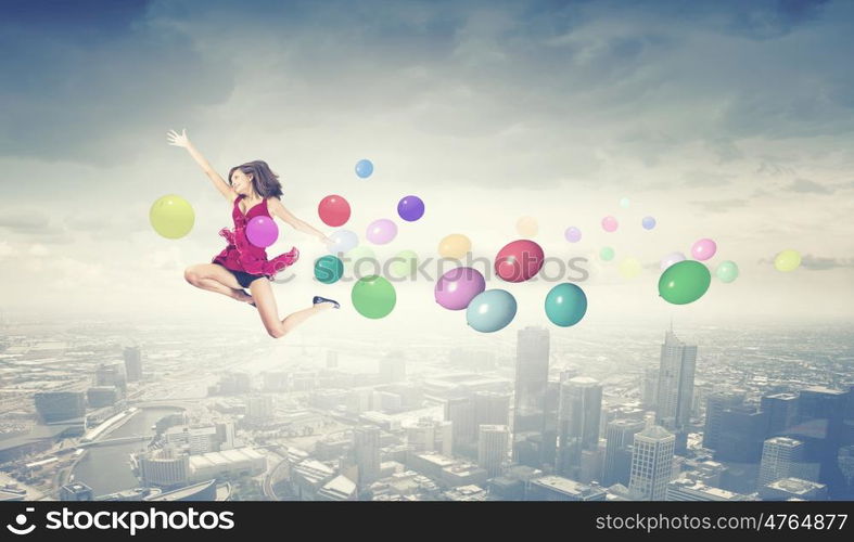 Young cheerful lady in red dress jumping high