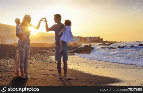 Young , cheerful parents making a heart sign