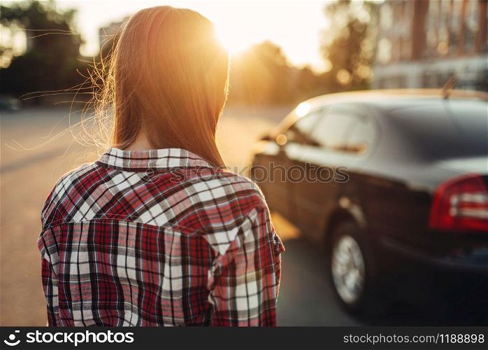 Young cheerful woman driver posing against a car. Female person and vehicle, automobile driving concept. Young cheerful woman driver posing against a car