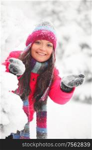 Young cheerful woman play snowballs in winter park. Winter woman play snowballs