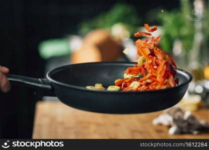 Young chef frying fresh vegetables. Motion blur . Vegetarian Restaurant Cooking - Frying Sliced Red Bell Pepper in Pan