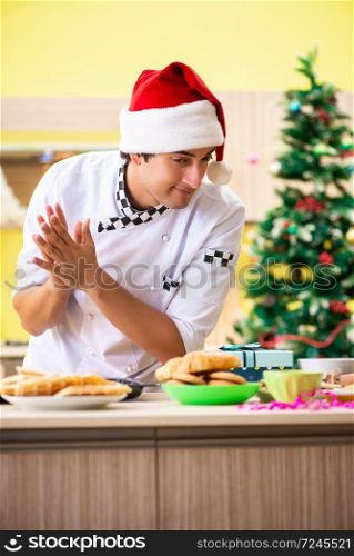 Young chef husband working in kitchen at Christmas eve . The young chef husband working in kitchen at christmas eve 