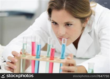 young chemistry teacher in school laboratory workplace looking at test-tube