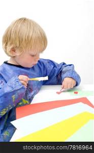 Young child cutting and pasting pieces of colorful paper