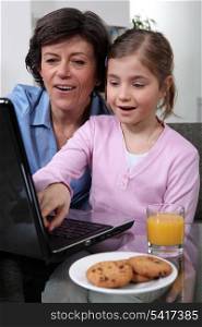 Young child looking at a laptop with her grandmother