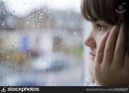 young child looking out of window on rainy day
