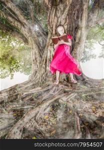 Young child reading glowing book next to a tree