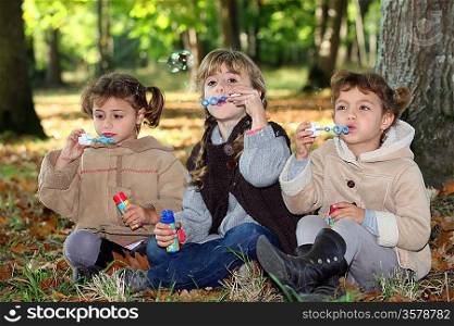 Young children blowing bubbles in the woods