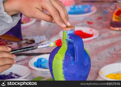 Young children decorating handmade clay pottery. Young children decorating their handmade clay pottery