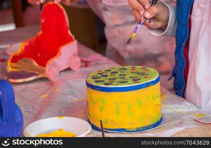 Young children decorating handmade drum