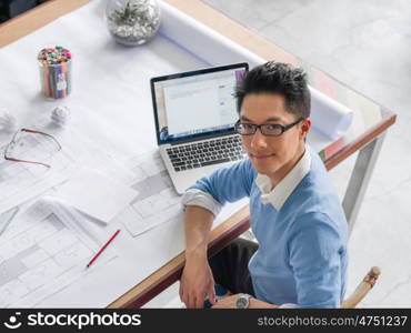 Young chineese engineer working in office. Getting your house plan ready