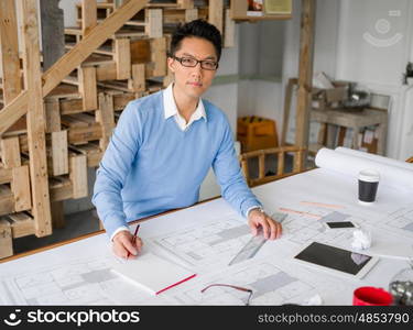 Young chineese engineer working in office. Getting your house plan ready