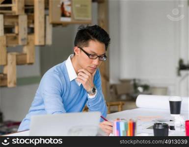 Young chineese engineer working in office. Getting your house plan ready