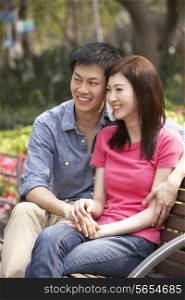Young Chinese Couple Relaxing On Park Bench Together