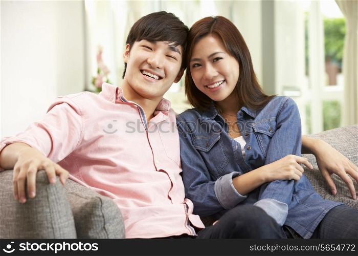 Young Chinese Couple Relaxing On Sofa At Home