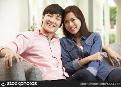 Young Chinese Couple Relaxing On Sofa At Home