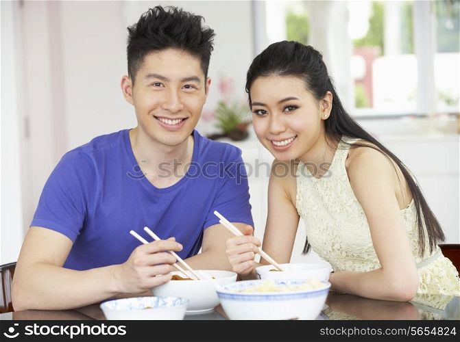 Young Chinese Couple Sitting At Home Eating Meal
