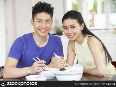 Young Chinese Couple Sitting At Home Eating Meal