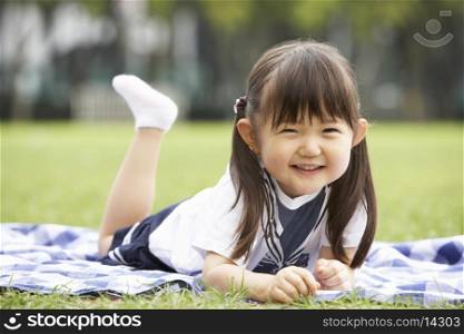 Young Chinese Girl Lying On Blanket In Park